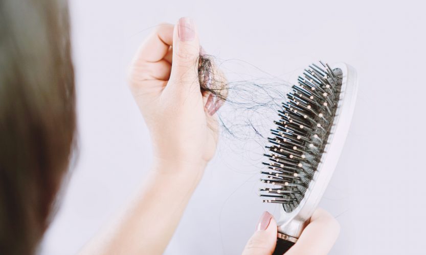 Asian woman hand holding hair loss falling on comb